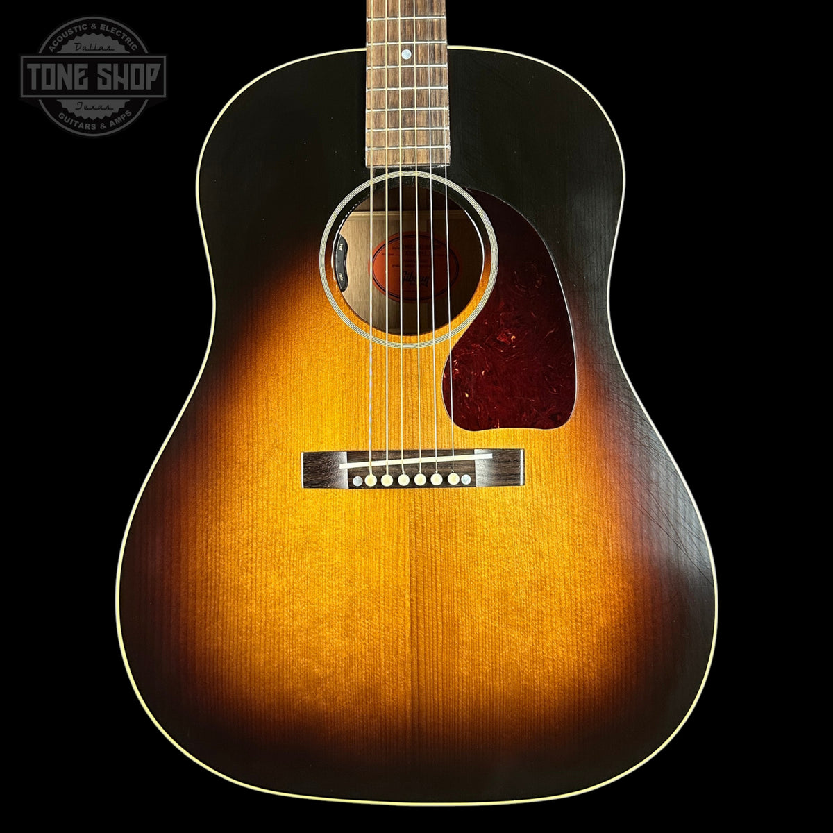 Acoustic guitar with a sunburst finish on a black background, featuring the Tone Shop logo.
