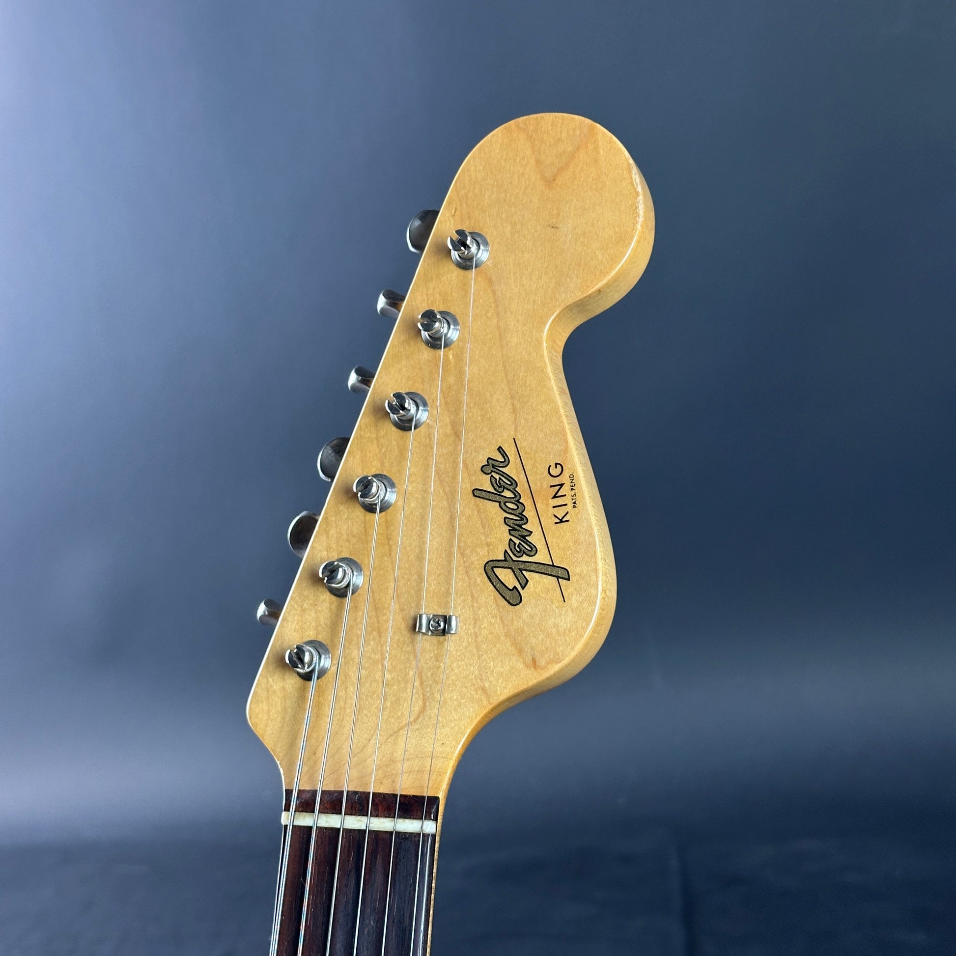Close-up of a Fender guitar headstock on a blue background