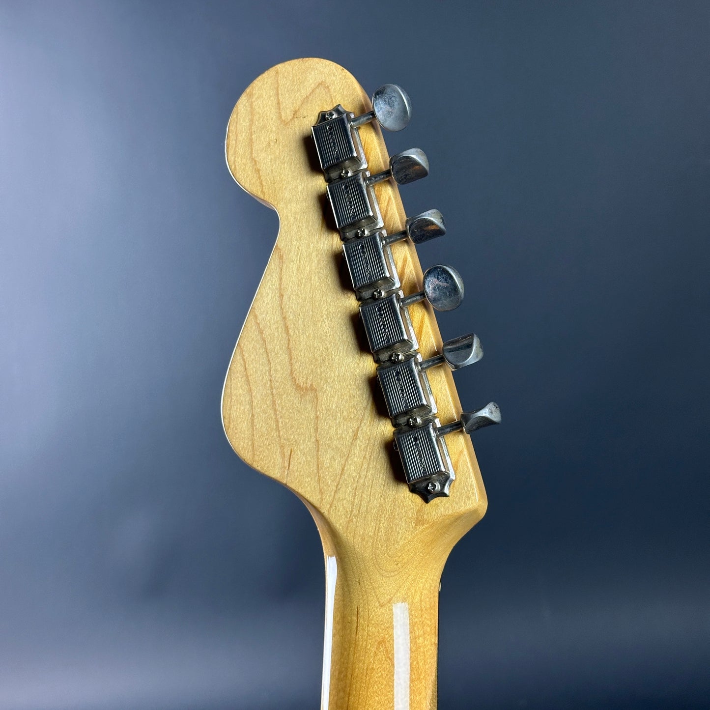 Guitar headstock with tuning pegs on a dark blue background