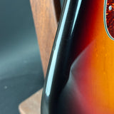 Close-up of a guitar neck and body with a dark finish.