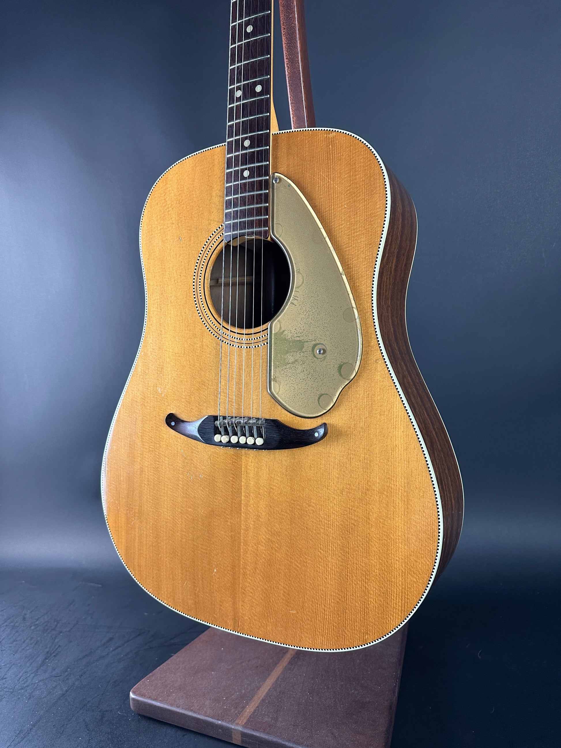 Acoustic guitar on a stand against a gradient blue background