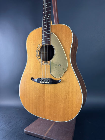 Acoustic guitar on a stand against a gradient blue background