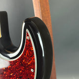 Close-up of a guitar's headstock with a black and red design on a gray background