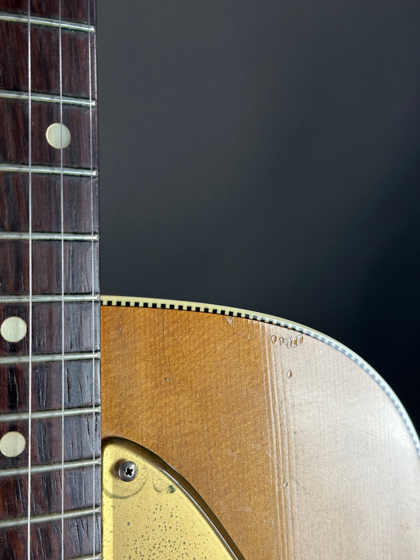 Close-up of a guitar's neck and headstock against a dark background