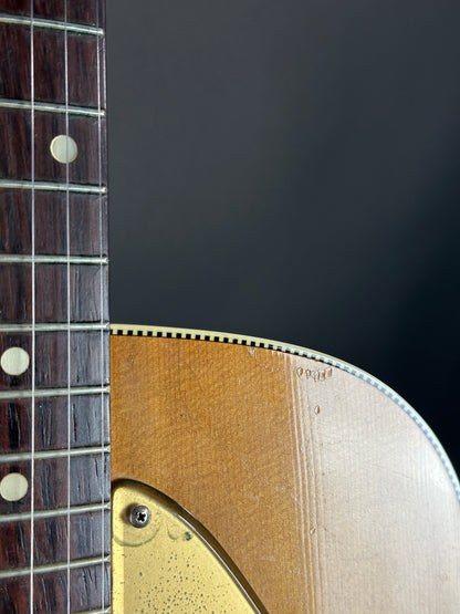 Close-up of a guitar's neck and headstock against a dark background