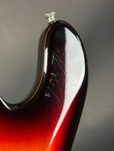 Close-up of a guitar neck with a red and black finish on a gray background