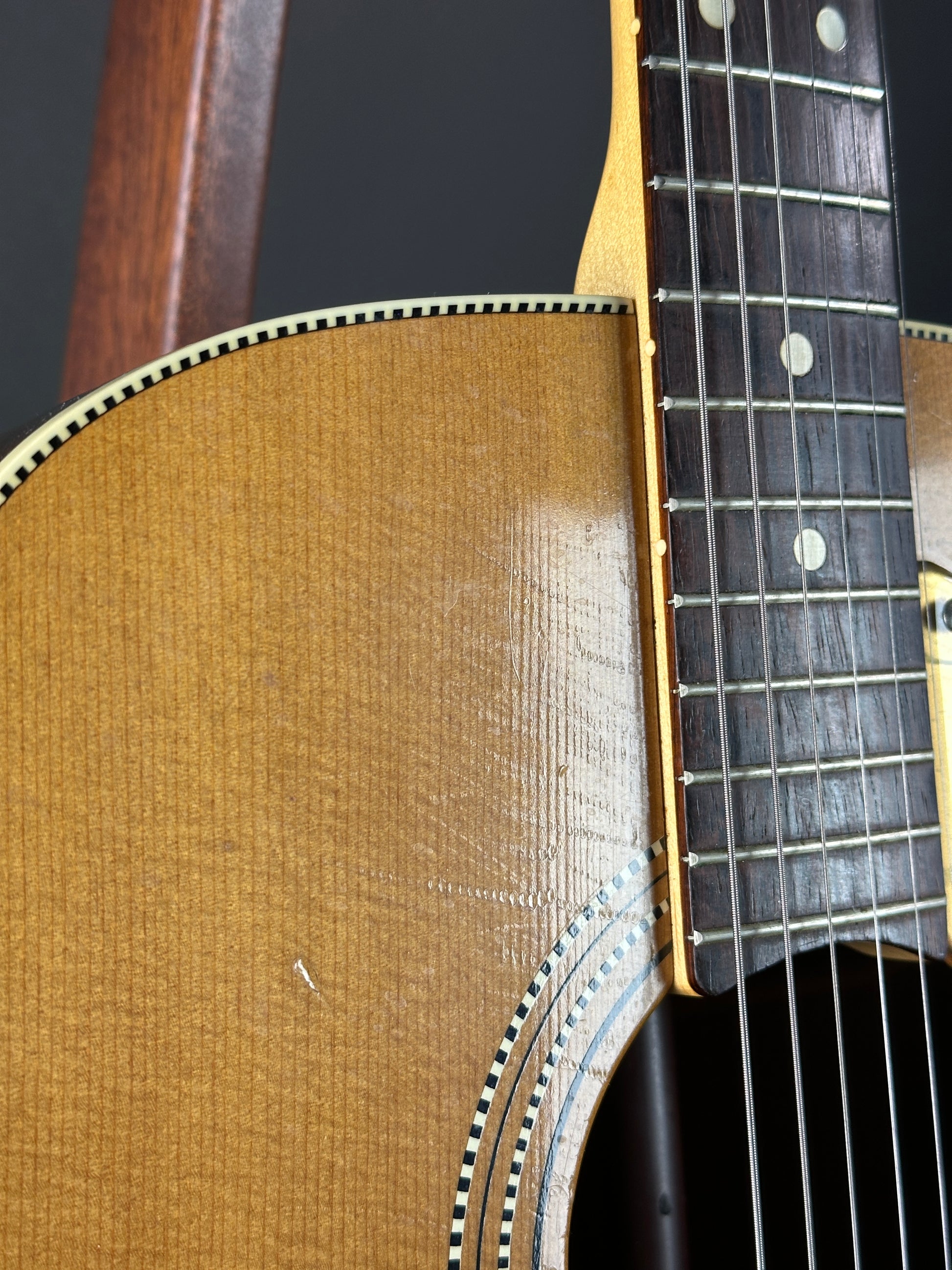 Close-up of an acoustic guitar's neck and body on a dark background