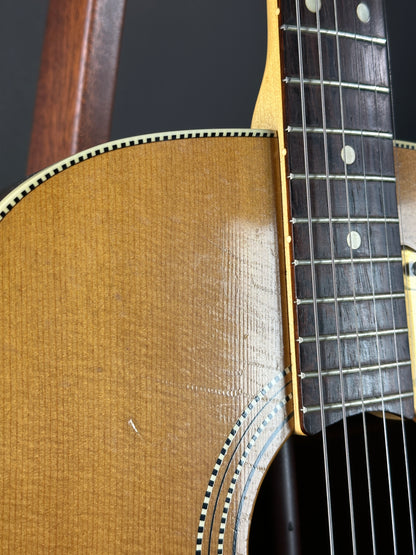Close-up of an acoustic guitar's neck and body on a dark background