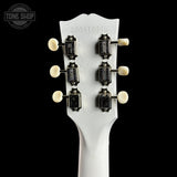 Close-up of the back of a white guitar headstock showing six black tuning pegs with cream-colored knobs, on a black background with a Tone Shop watermark in the top left.