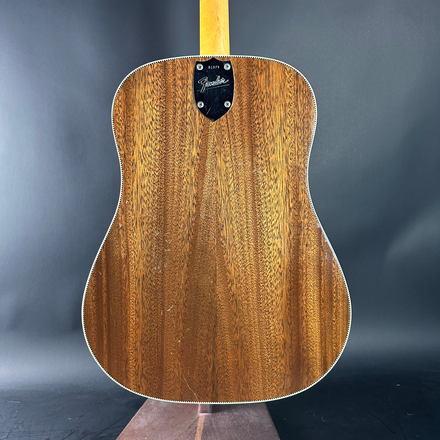 Wooden acoustic guitar with Fender logo on a dark gray background
