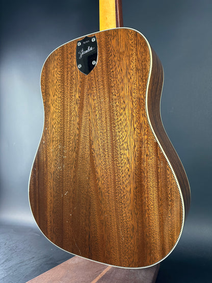 Acoustic guitar with a focus on the wooden body against a gray background