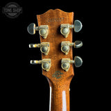 Close-up of a guitar headstock with tuning pegs on a black background, featuring 'Tone Shop' branding.