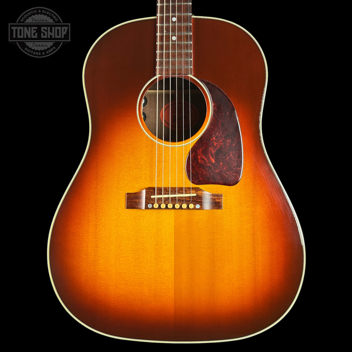 Acoustic guitar with a sunburst finish on a black background, featuring the Tone Shop logo.