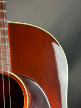 Close-up of an acoustic guitar's body and neck on a dark background