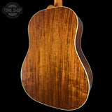 Back view of a wooden acoustic guitar with 'Tone Shop' logo.