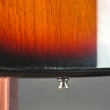Close-up of a wooden object with a sunburst finish, showing a dark rim and a small silver metal cap or knob below it.