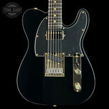 Black electric guitar with a clear finish on a black background, featuring the Tone Shop logo.
