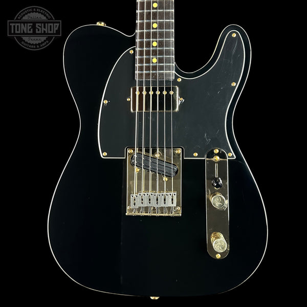 Black electric guitar with a clear finish on a black background, featuring the Tone Shop logo.