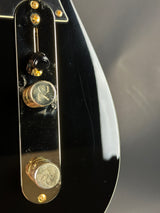 Close-up of a guitar pickup with gold and black components on a dark background
