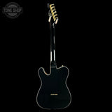 Black electric guitar with gold hardware on a black background, featuring 'Tone Shop' logo.