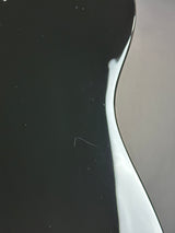 A close-up of a glossy black surface with a curved white highlight line and a neutral gray area on the right side.