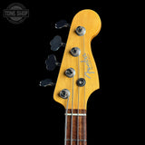 Close-up of a Fender bass guitar headstock with a natural maple finish, four black tuning pegs, and a dark wood fretboard against a black background.