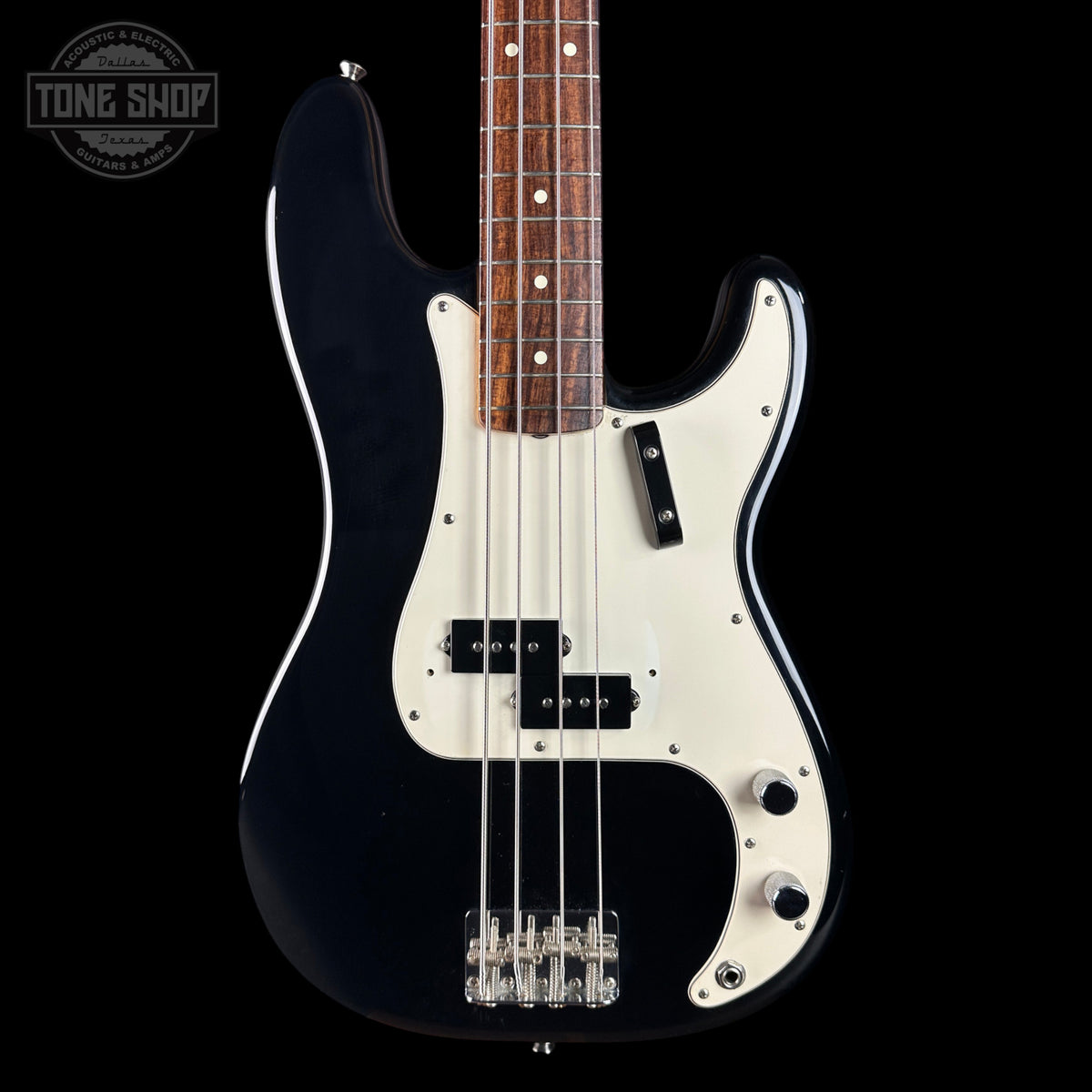 A black and white electric bass guitar with a dark wood fretboard, shown from the front against a black background. A Tone Shop watermark is visible in the top-left corner.