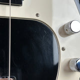 Close-up of a cream-colored electric guitar body with a black pickguard, chrome control knobs, and a visible string, showing some surface scratches on the glossy black area.