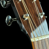 Close-up of a guitar's headstock with tuning pegs on a dark background