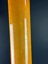 Close-up of a glossy, warm golden-brown wooden surface with visible wood grain and two vertical white light reflections against a dark background.