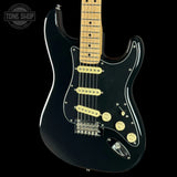 A black electric guitar with a maple neck and cream-colored pickups, shown against a solid black background with a Tone Shop watermark in the top left corner.