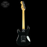 A black electric guitar shown from the back against a solid black background, featuring a maple neck and a white pickguard.