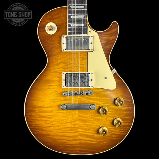 A classic electric guitar with a natural sunburst finish, featuring a cream pickguard, dual humbucker pickups, and gold-toned hardware, shown against a solid black background.