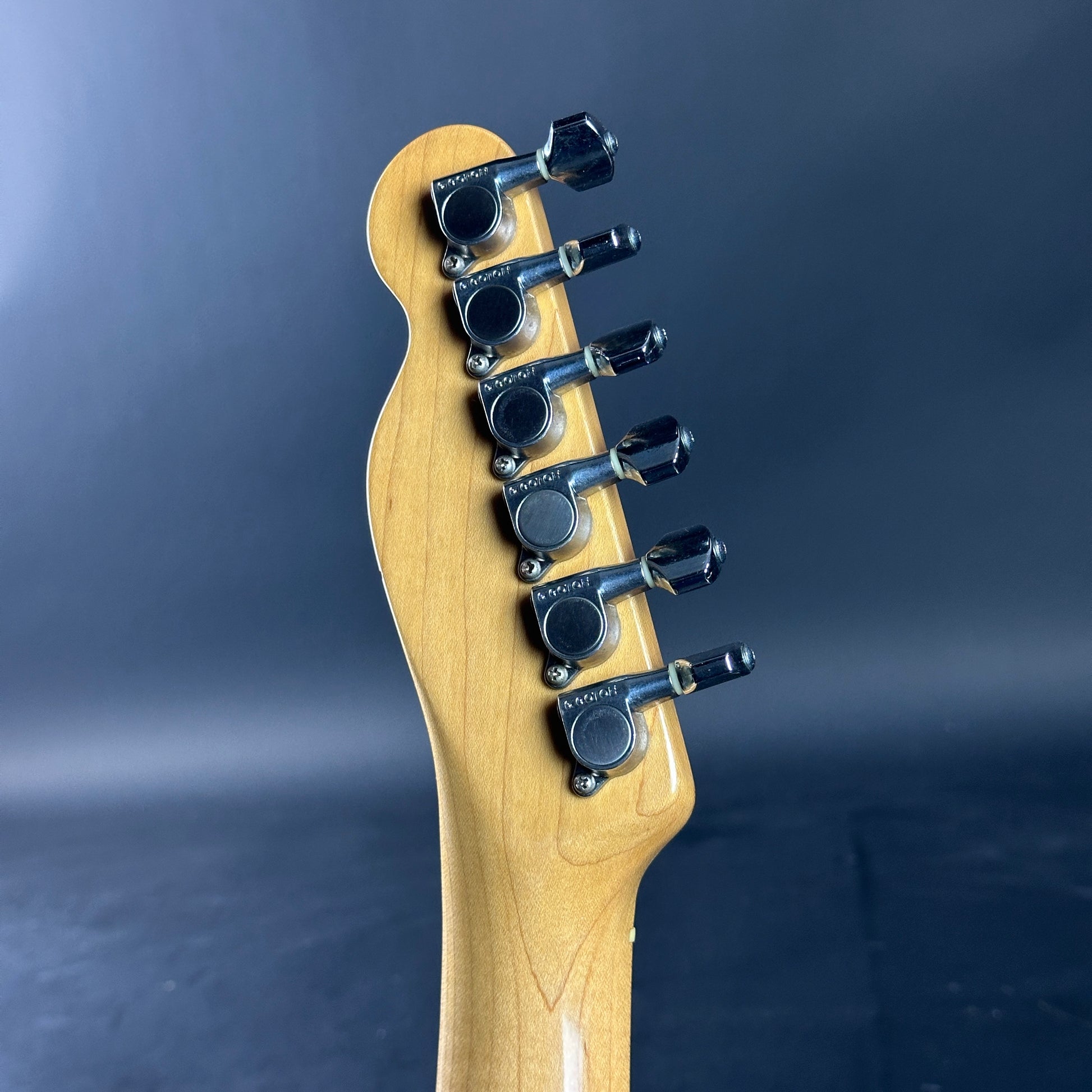 Guitar headstock with tuning pegs on a dark background