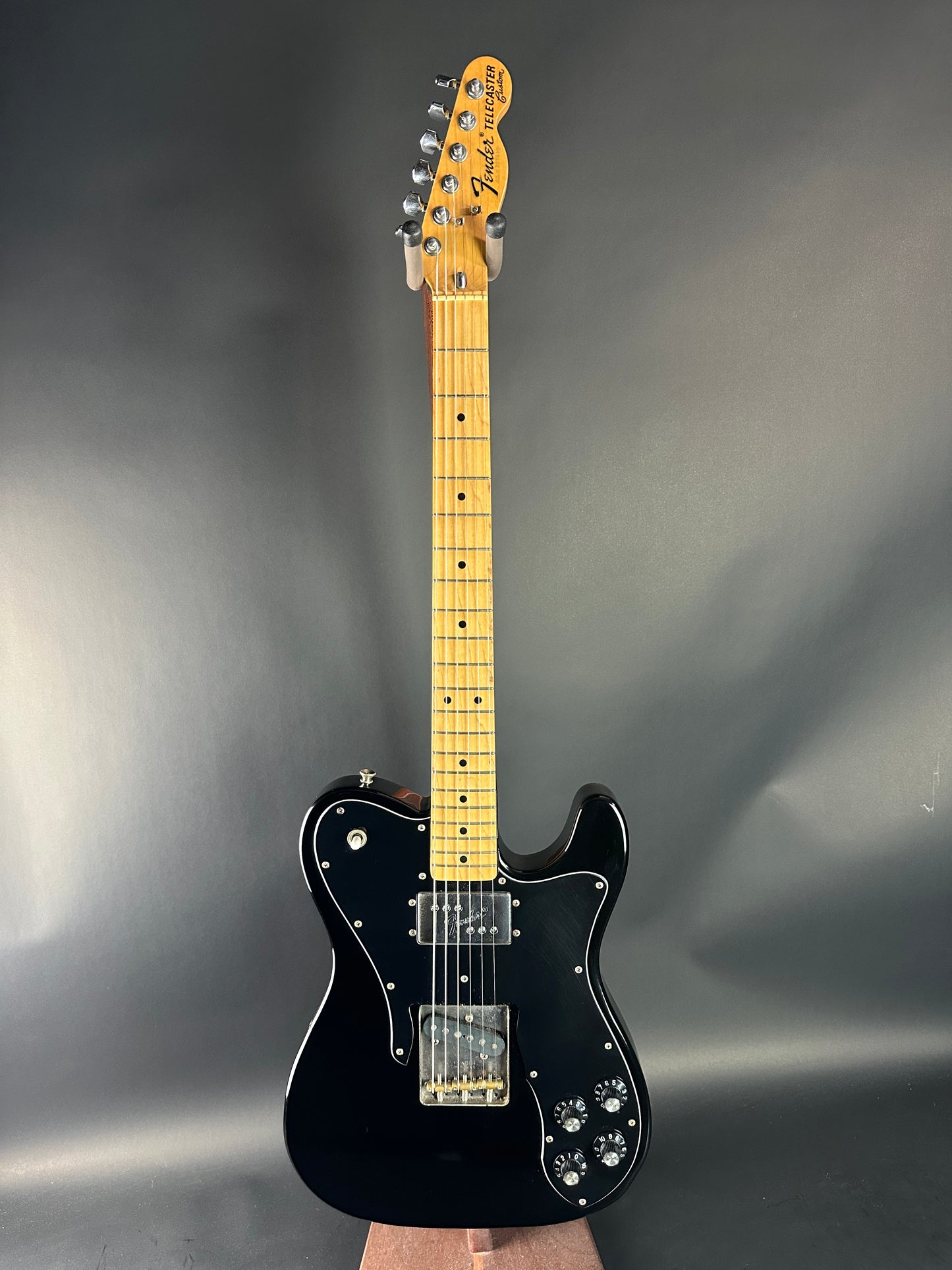 Black electric guitar on a gray background