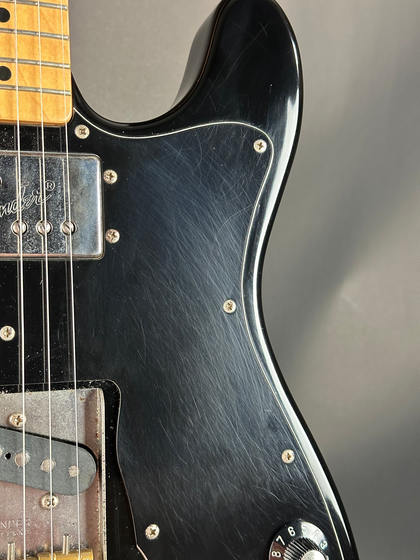 Close-up of a black electric guitar with a blurred gray background