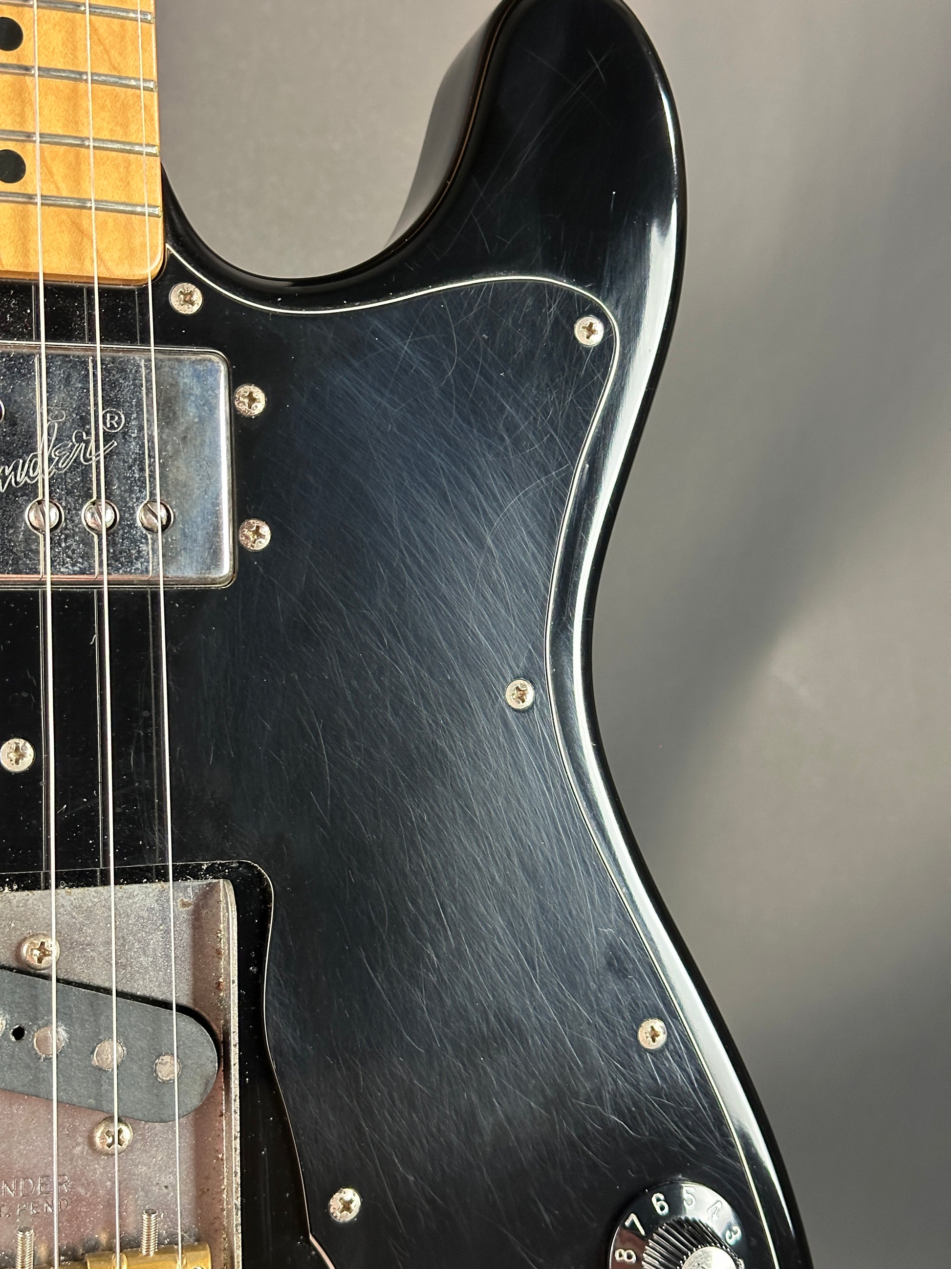 Close-up of a black electric guitar with a blurred gray background