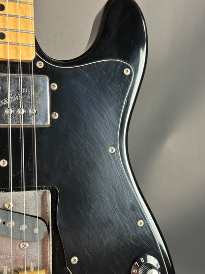 Close-up of a black electric guitar with a blurred gray background