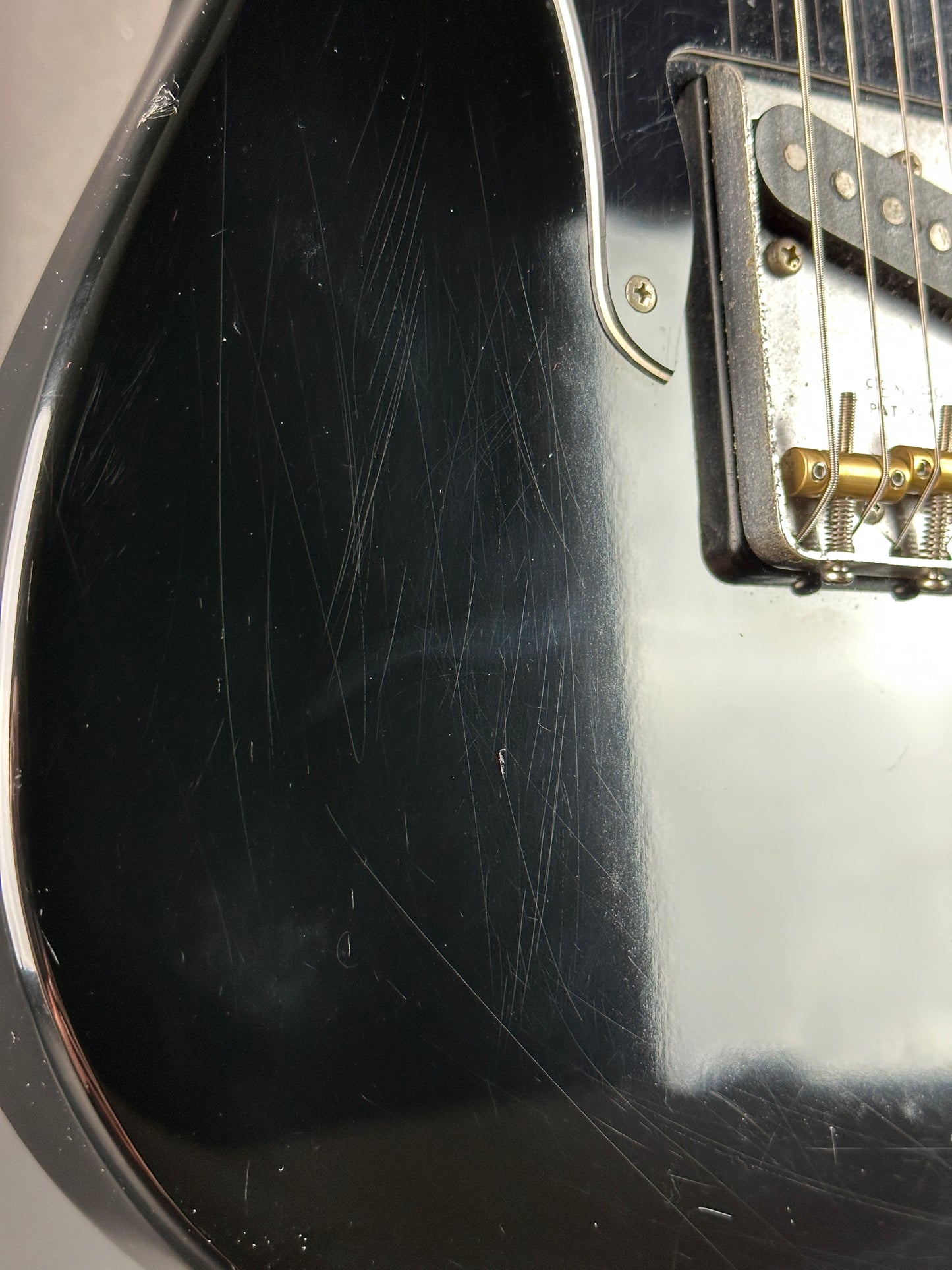 Close-up of a black electric guitar with visible wear and tear on the body.