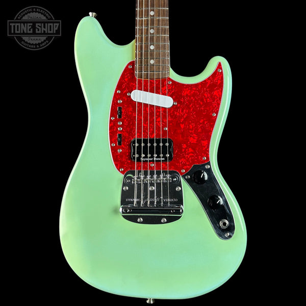 Electric guitar with a green body and red pickguard on a black background, featuring 'Tone Shop' branding.