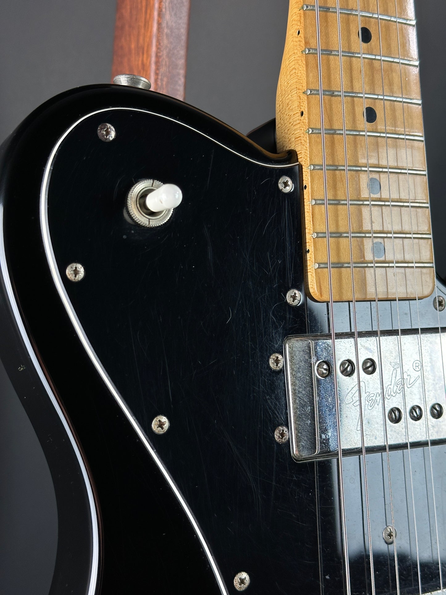 Close-up of a black electric guitar with visible hardware and wood finish.