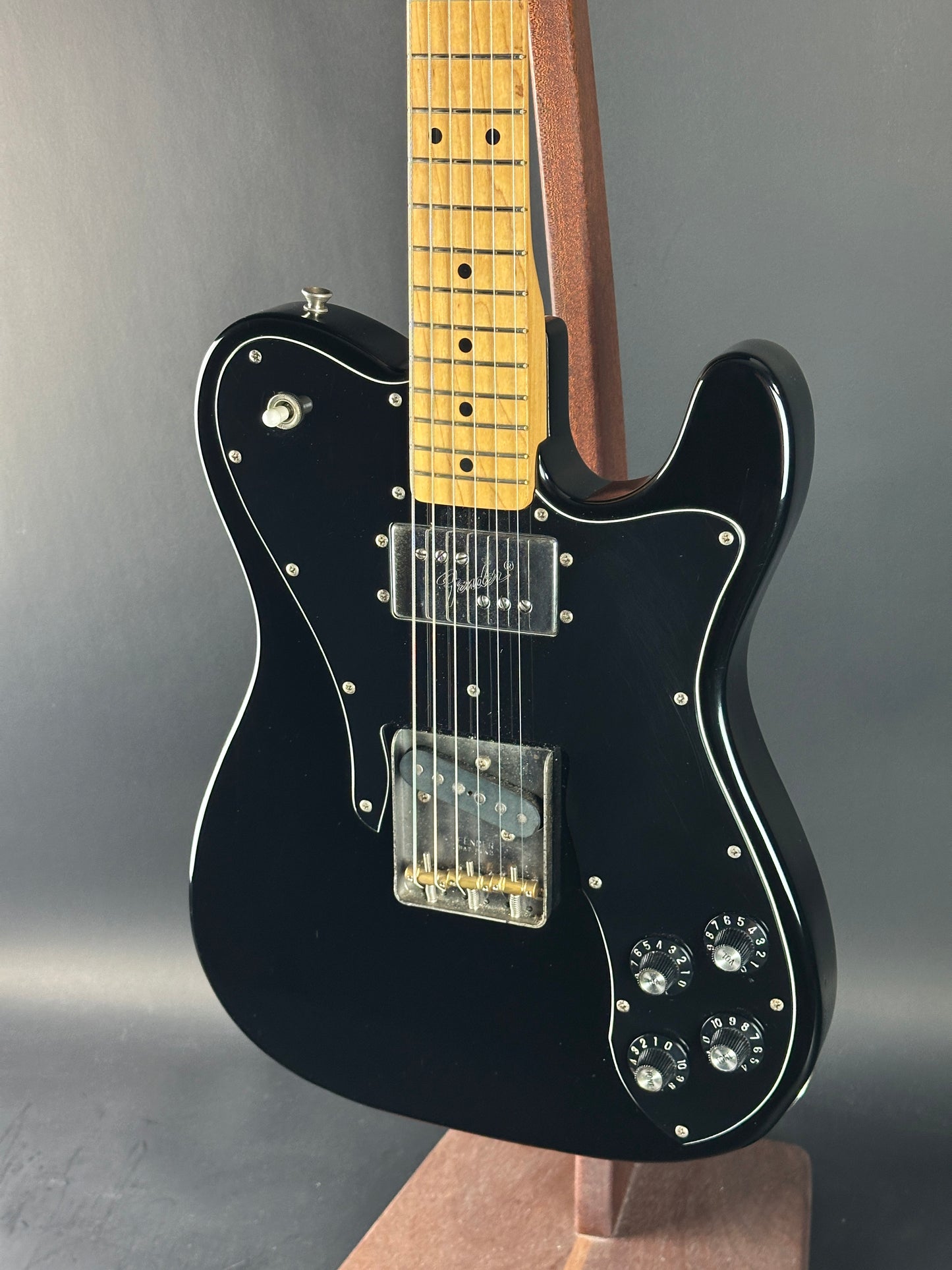 Black electric guitar on a gray surface with a neutral background