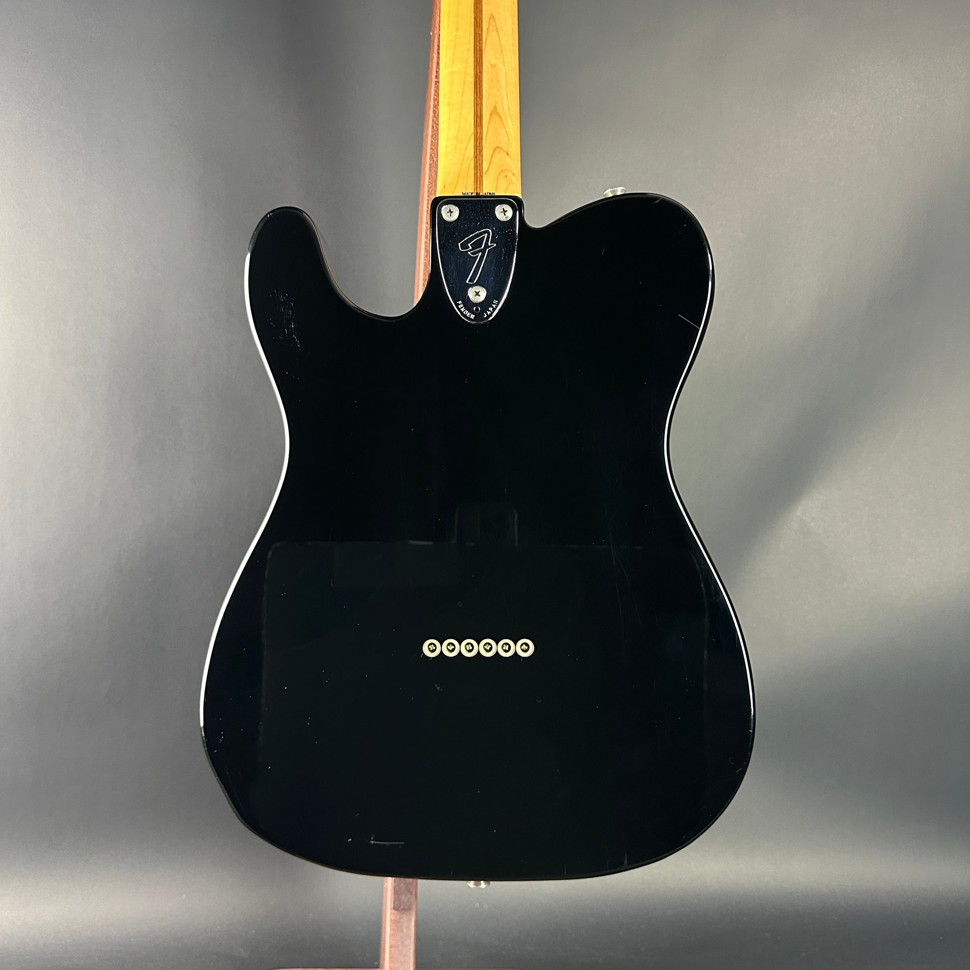 Black electric guitar with a Fender logo on a gray background