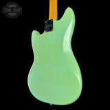 Green electric guitar with a black pickguard on a black background, featuring 'Tone Shop' branding.
