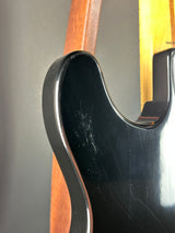 Close-up of a guitar's neck and headstock with a black pickguard.