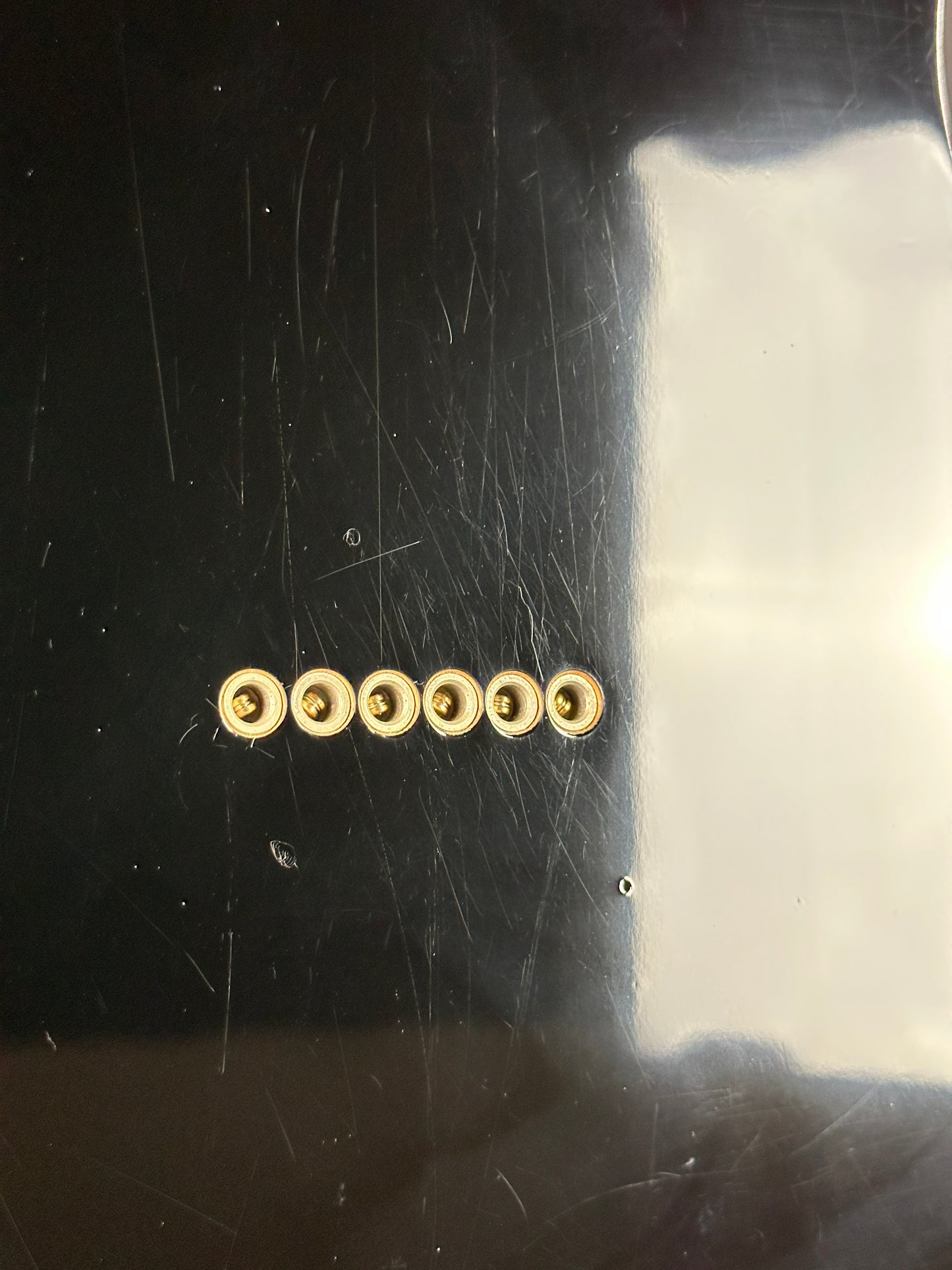 Row of gold screws on a scratched metal surface
