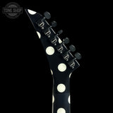 Close-up of a black electric guitar headstock with large white polka dots and six black tuning pegs, shown against a black background with a Tone Shop watermark in the top left.