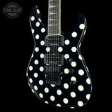 A black electric guitar with a bold white polka dot pattern, shown against a solid black background. The Tone Shop logo is visible in the top-left corner.