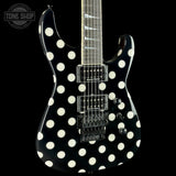 A black electric guitar with large white polka dots, shown against a solid black background. The brand 'Tone Shop' is visible as an overlay in the top-left corner.