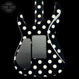 A black electric guitar body with a white polka dot pattern, featuring a satin black pickguard and a brushed silver metal plate on the lower bout, shown against a solid black background.